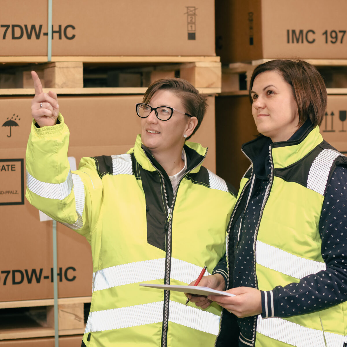 Zwei Mitarbeiterinnen in Warnwesten stehen im Lager von Tillmann Verpackungen