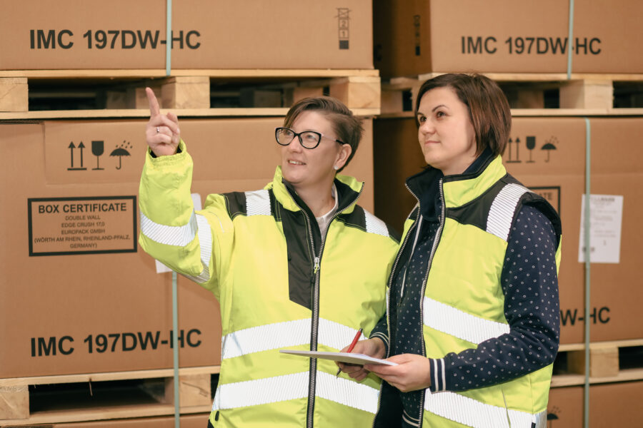 Zwei Mitarbeiterinnen in Warnwesten stehen im Lager von Tillmann Verpackungen